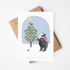 Christmas card with a bear decorating a tree, envelope on a white background